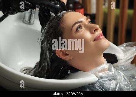 Hairdresser rinsing out dye from woman's hair in beauty salon Stock Photo