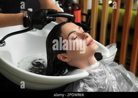 Hairdresser rinsing out dye from woman's hair in beauty salon Stock Photo