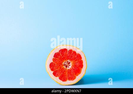 Grapefruit on a blue background. Exotic fruit for diet. Juicy slice of ripe grapefruit. Stock Photo