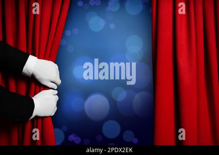 Man opening red front curtains against blurred lights. Bokeh effect Stock Photo