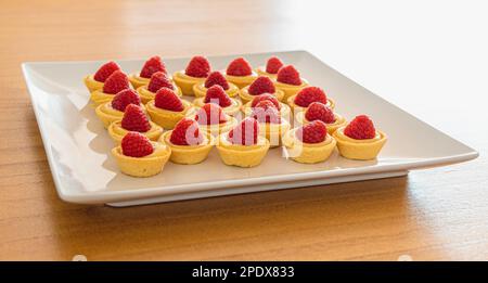 Raspberry tartlets with lemon curd on a white plate. Elegant pastry dessert Stock Photo