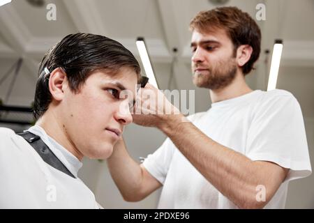 Barber talking to caucasian man while sitting in chair Stock Photo