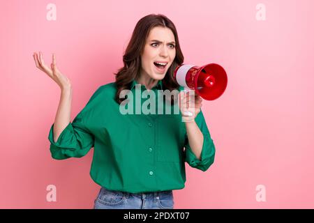 Photo of angry bossy woman wavy hairdo dressed green shirt shouting in loudspeaker blaming look empty space isolated on pink background Stock Photo