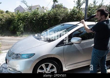 two measles  cleaning a  silver  car  spraying  foam  with a  pressure washer   washing  a  car Stock Photo