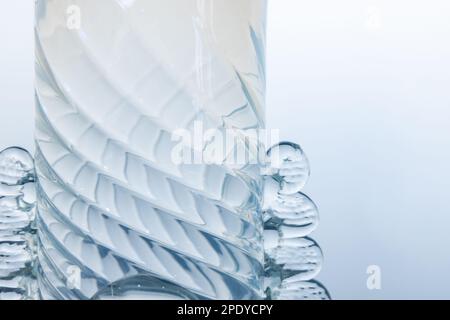 Fragment of transparent empty vase over light blue wall background. Abstract glass installation Stock Photo