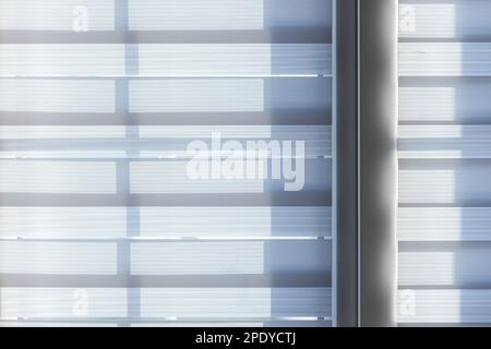 Textile translucent blinds on a window on a sunny day, abstract background photo Stock Photo