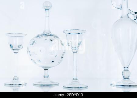 Transparent empty glasses and decanters over light blue background. Abstract glass installation Stock Photo