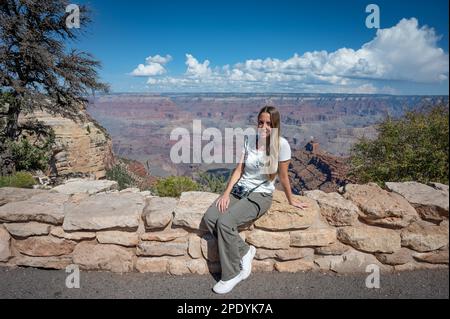 Portrait of a young girl sitting on the low wall of the viewpoint of the Grand Canyon Stock Photo