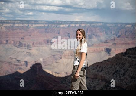 Young blonde girl with a photo camera in front of the landscape of the Grand Canyon Stock Photo