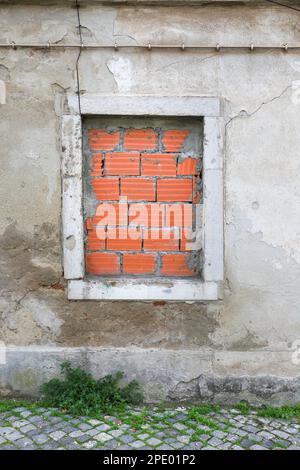 Window bricked up with red bricks of abandoned building Stock Photo