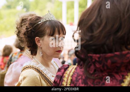 Khabarovsk, Russia - June 2, 2018: Two middle-aged ladies wearing historical costumes at a ball. One woman in a formal dress looks at another with env Stock Photo