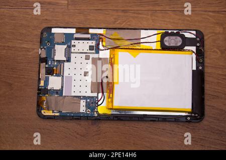 broken tablet disassembled on a wooden background Stock Photo