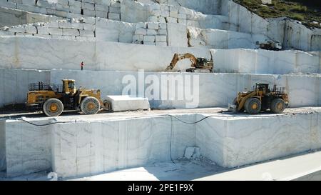 Heavy machines working at a huge marble quarry in Europe. Transporting the marble blocks. Stock Photo