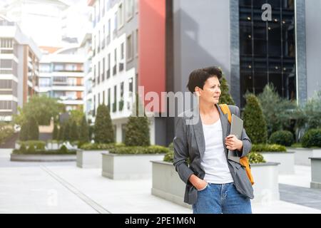 A stylish middle-aged business woman walks through the business center.  Stock Photo