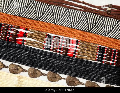 Fashionable collection of various boho style belts arranged in a row. Flat lay of many different women belts, braided, beaded, metal, woven Stock Photo
