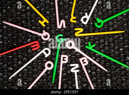 Colorful plastic sticks with English letters on top scattered on black. Word go in the center. Fun educational toy for kids learning alphabet Stock Photo