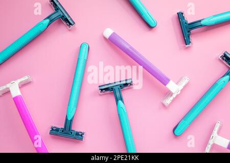 Many disposable purple and blue razors on a pink background. Colorful women and men hygiene accessories flat lay Stock Photo