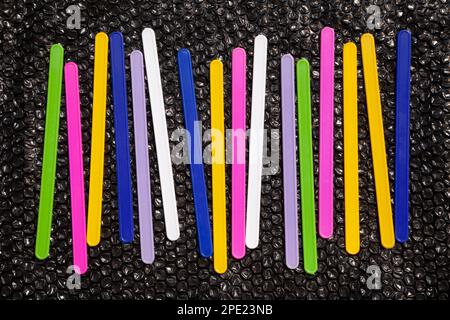 16 colorful lines on black, abstract geometric background. Plastic counting sticks, number learning tool for kids Stock Photo