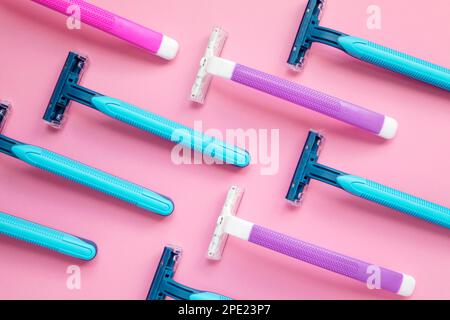 Many disposable purple and blue razors on a pink background. Colorful women and men hygiene accessories flat lay Stock Photo