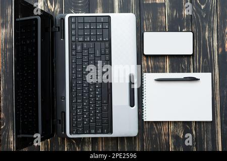 Home workplace. Blank notebook, laptop, pen and mobile on a dark background nice Stock Photo