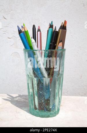 Bunch of assorted colored pencils and other art tools stored in a glass. Artist materials for drawing Stock Photo