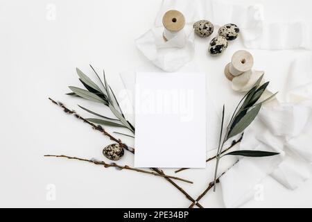 Easter, spring still life. Blank greeting card, invitation mockup isolated on white table background. Quail eggs, silk ribbons, green olive tree Stock Photo