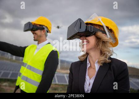 Two engineers work using virtual reality headsets at a solar power plant. Stock Photo