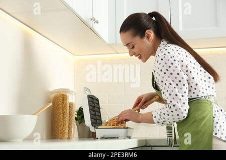 Woman making delicious Belgian waffles in kitchen Stock Photo