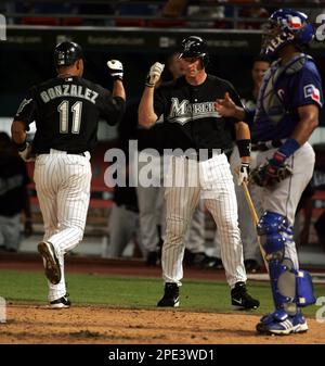 Texas Rangers' Juan Gonzalez, center, receives congratulations from  teammates Alex Rodriguez and Rafael Palmeiro after driving them in with a  three-run homer as Boston Red Sox catcherJason Varitek looks on in the