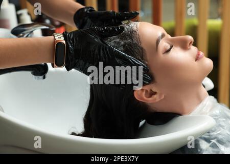 Hairdresser rinsing out dye from woman's hair in beauty salon Stock Photo