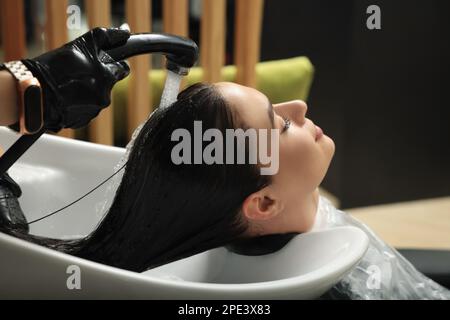 Hairdresser rinsing out dye from woman's hair in beauty salon Stock Photo