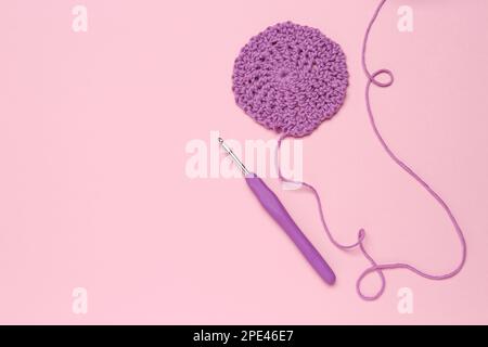 knitting pink crochet hooks and woolen thread on a blue background