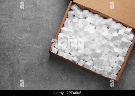 Cardboard box filled with polystyrene styrofoam pieces on grey background, top view. Space for text Stock Photo