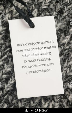 Close up of luxury clothing hang tag. Delicate garment swing tag. Laundry care washing instructions clothes label. Stock Photo