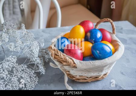 easter bright colored eggs in the easter egg basket. Festive Easter multicolored eggs on a wooden background. Stock Photo