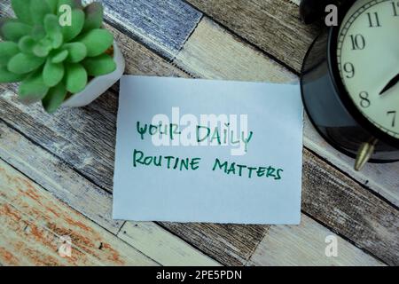 Concept of Your Daily Routine Matters write on sticky notes isolated on Wooden Table. Stock Photo