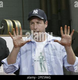 Actor Adam Sandler holds up his hands after placing them in wet cement ...