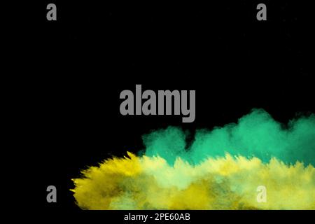 Yellow and green dust explosion on black background. Abstract yellow green powder splattered. Stock Photo