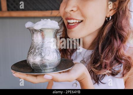 Girl drinks a traditional Kazakh and Asian fermented milk drink from mare's milk - koumiss from a silver mug with foam Stock Photo