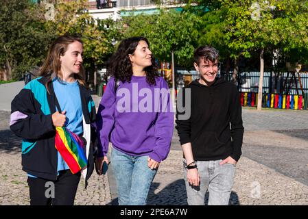 Young diverse friends walking on the street with the lgbt rainbow flag. Stock Photo
