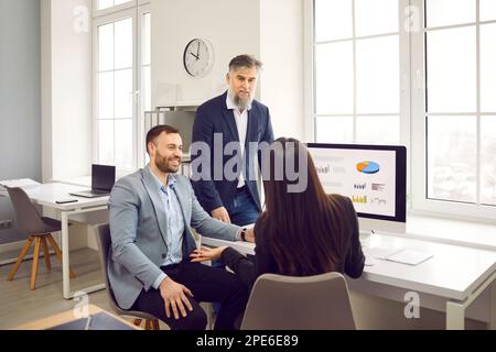 Business team having a work meeting, discussing their strategy, and using a computer Stock Photo