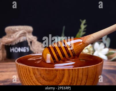 Honey spoon coming out of the bow full of honey. Honey contains many nutrients, antioxidants, improves heart health, wound care, offers antidepressant Stock Photo