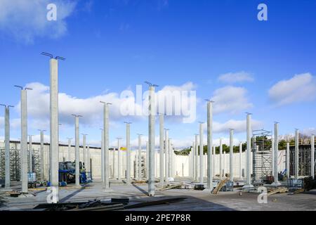 Many white vertical reinforced concrete columns at the construction site of an industrial facility, blue sky background Stock Photo