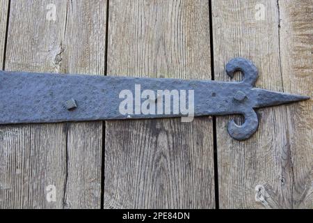 Close up of unusually, large hinge on old wooden door. Pointed end with arrow.  Located on a Connecticut state park building. Stock Photo