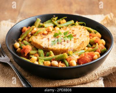 Green Bean and Tomato Stew with Chickpeas and a vegan cutlet Stock Photo