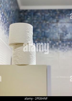 rolls of white toilet paper on the cabinet in the bathroom interior. Stock Photo