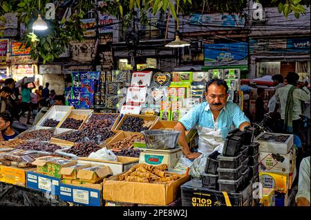 A salesman is selling nuts, dried fruit and many different spices in his shop in the the spice market in Old Delhi Stock Photo