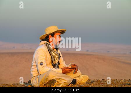 Young Egyptian man sitting alone on a sand dune in the Western desert near Cairo Stock Photo