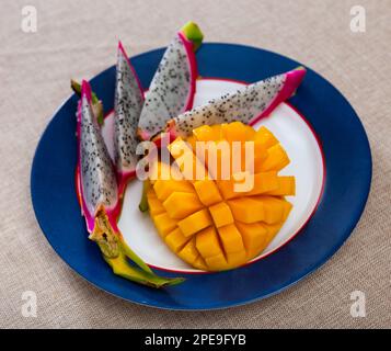 Slices of ripe juicy mango and pitaya on plate Stock Photo
