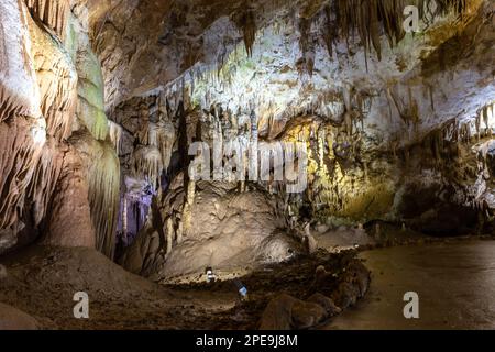 Prometheus Cave Natural Monument - largest cave in Georgia with hanging stone curtains, stalactites and stalagmites, colorful illuminated walls. Stock Photo